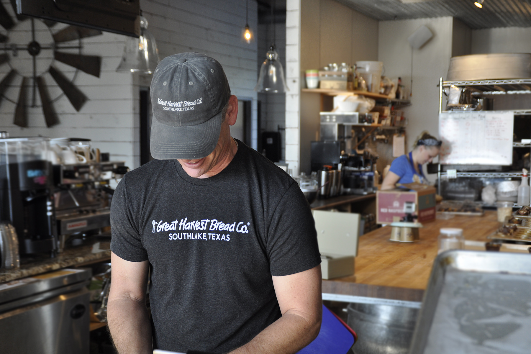 Great Harvest worker wearing a dark t-shirt prepares an item